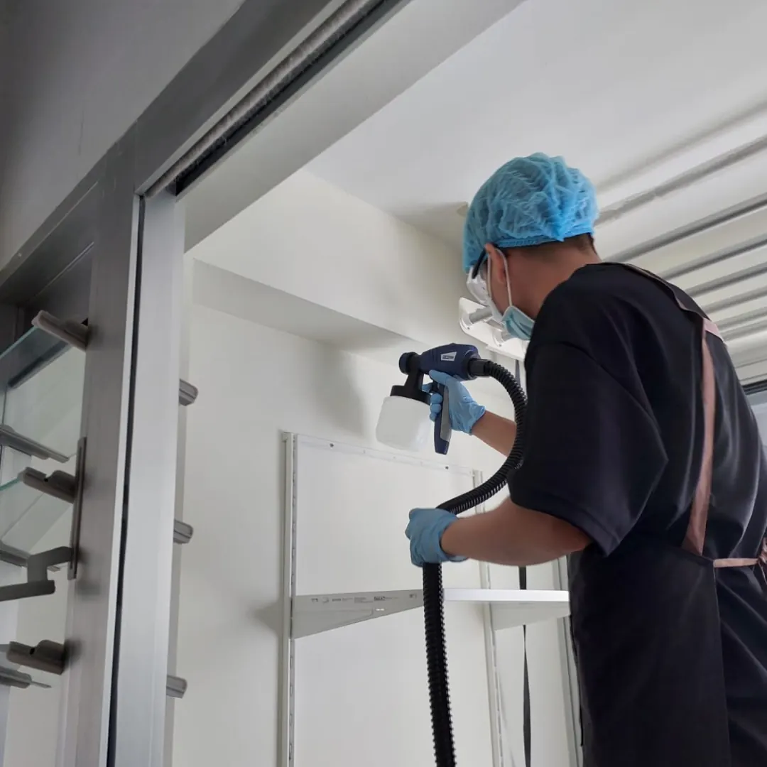 Pico X Health technician applies anti-mould spray treatment to ceiling using HVLP sprayer in full PPE - Singapore